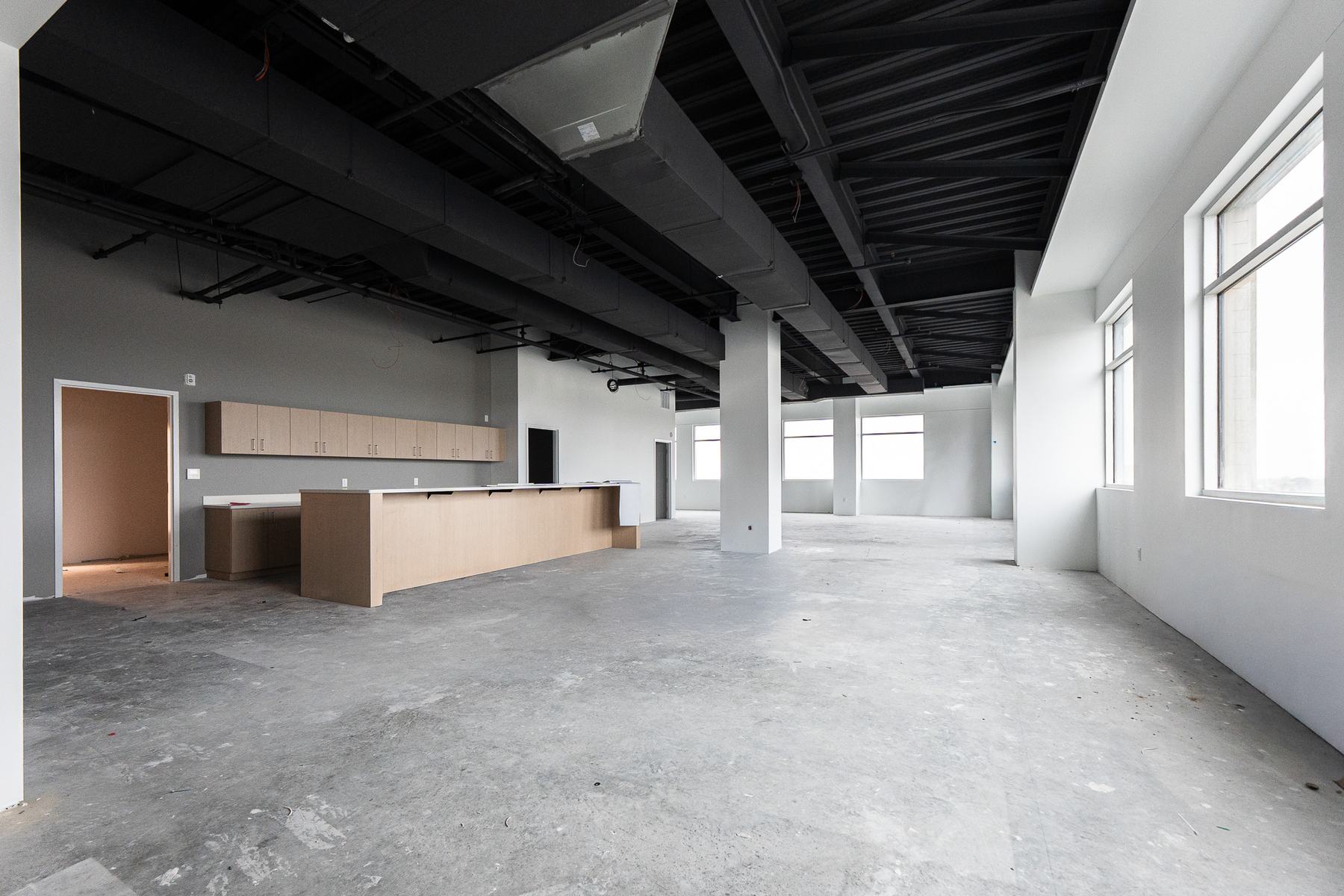 Open office with a kitchen island and exposed ceiling