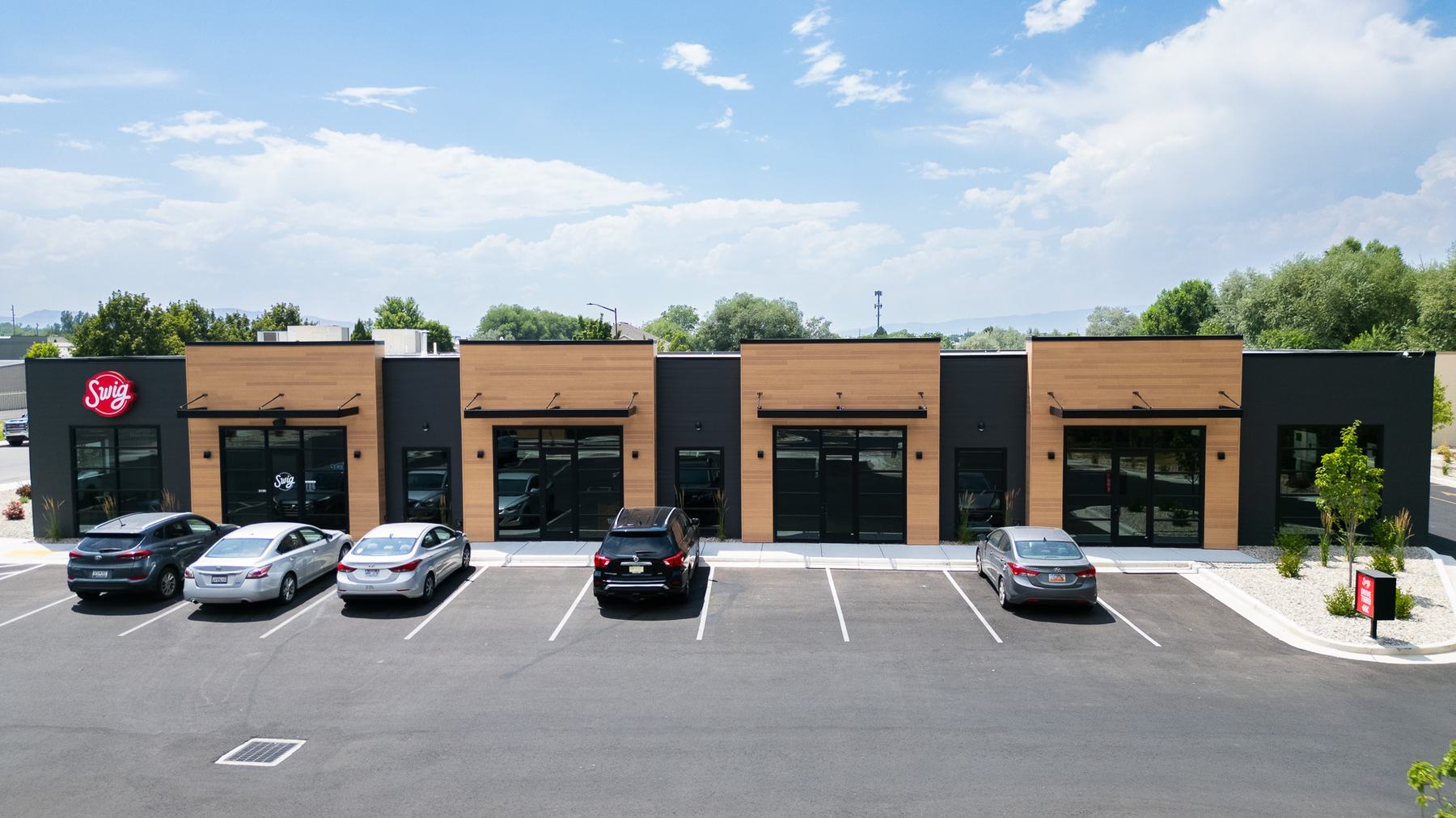 Multi-tenant retail building with wood and dark panel storefronts